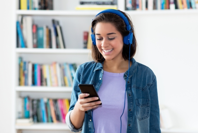 young adult woman listening to podcast indoors at home